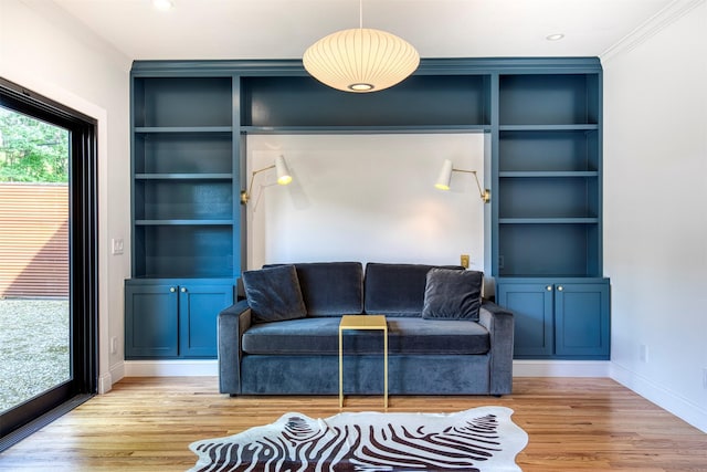 living room with built in shelves, baseboards, and light wood-style flooring