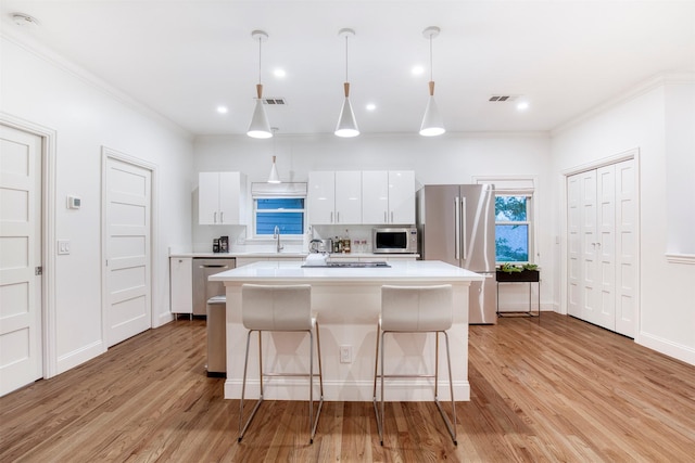 kitchen featuring appliances with stainless steel finishes, a breakfast bar area, light countertops, a center island, and white cabinetry