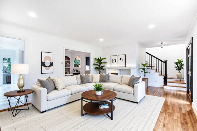 living room featuring stairway, baseboards, ornamental molding, recessed lighting, and light wood-style flooring