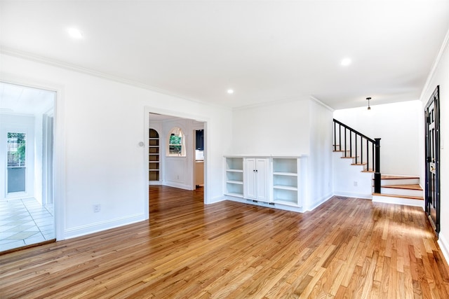 unfurnished living room with crown molding, baseboards, stairway, and light wood-style floors