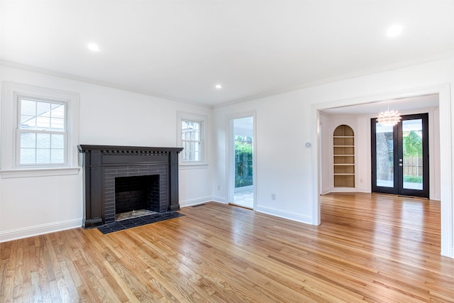 unfurnished living room featuring baseboards, a brick fireplace, light wood-style flooring, and a wealth of natural light