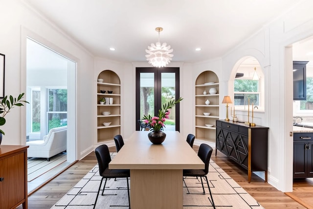 dining space featuring built in features, ornamental molding, and light wood-style floors