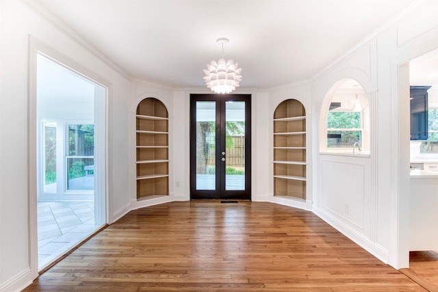 doorway with wood finished floors, a notable chandelier, and built in shelves