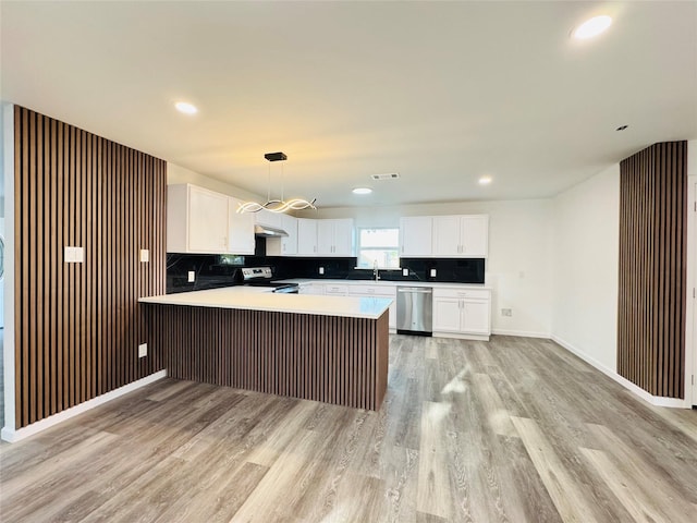 kitchen featuring a sink, a peninsula, stainless steel appliances, and light wood-style flooring