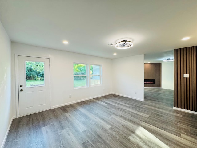 unfurnished living room featuring baseboards, a wealth of natural light, wood finished floors, and a fireplace