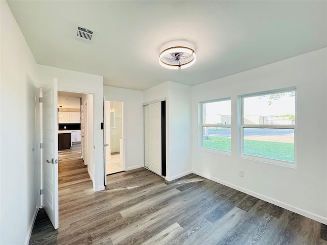 unfurnished bedroom featuring baseboards, wood finished floors, and visible vents