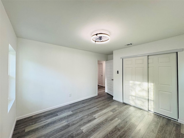 unfurnished bedroom featuring baseboards, wood finished floors, and visible vents