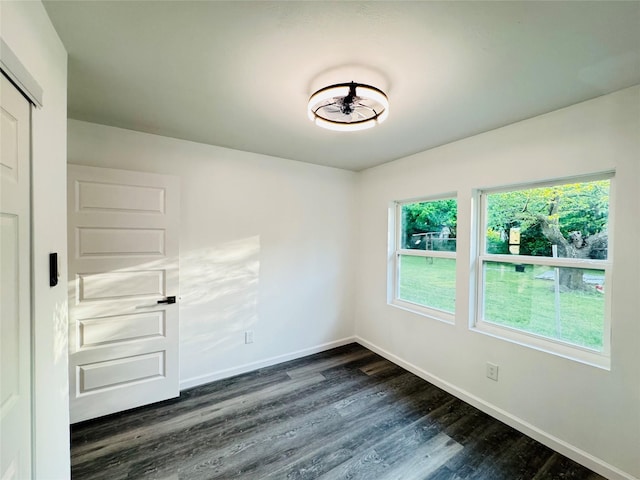 empty room with dark wood-type flooring and baseboards