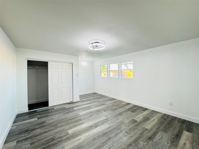 unfurnished bedroom with baseboards, wood finished floors, and a closet