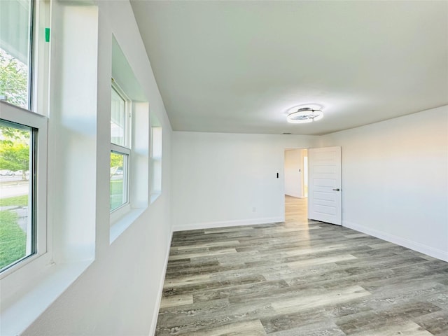 spare room with baseboards, a healthy amount of sunlight, and wood finished floors
