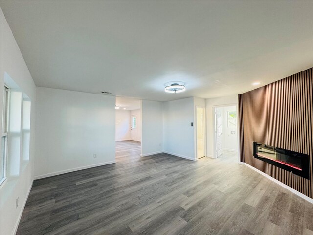 unfurnished living room featuring baseboards, a glass covered fireplace, and wood finished floors