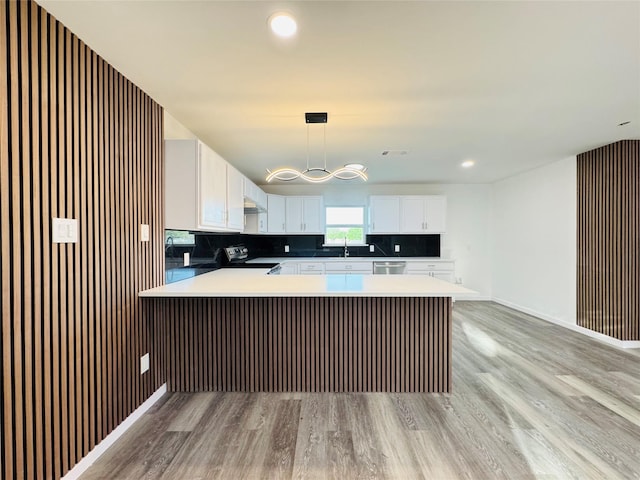 kitchen featuring a peninsula, a sink, white cabinetry, light wood-style floors, and appliances with stainless steel finishes