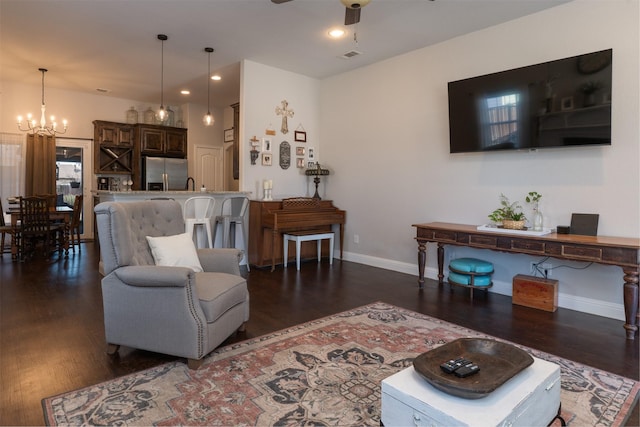 living area featuring recessed lighting, baseboards, dark wood-style flooring, and ceiling fan with notable chandelier