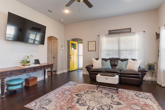 living area featuring arched walkways, a ceiling fan, wood finished floors, and visible vents