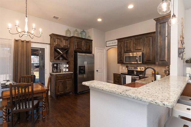 kitchen featuring visible vents, dark wood-type flooring, dark brown cabinetry, appliances with stainless steel finishes, and a notable chandelier