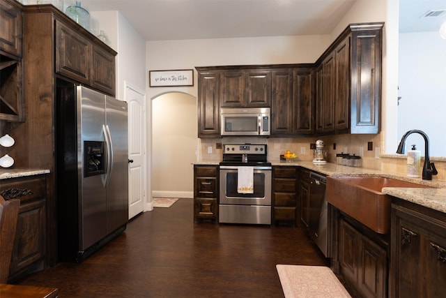 kitchen with stainless steel appliances, visible vents, a sink, dark brown cabinetry, and dark wood-style flooring