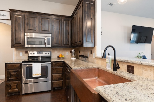 kitchen featuring stainless steel appliances, visible vents, a sink, dark wood-type flooring, and dark brown cabinetry
