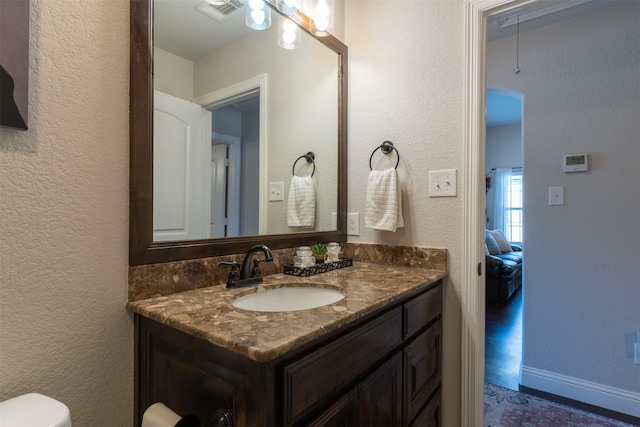 bathroom featuring a textured wall, visible vents, toilet, and vanity
