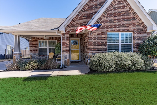 single story home featuring a front lawn, a ceiling fan, and brick siding