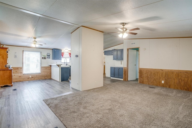 7203 Pump Station Rd, Jacksboro, TX 76458 - unfurnished living room featuring ceiling fan, wooden walls, wainscoting, a textured ceiling, and wood finished floors