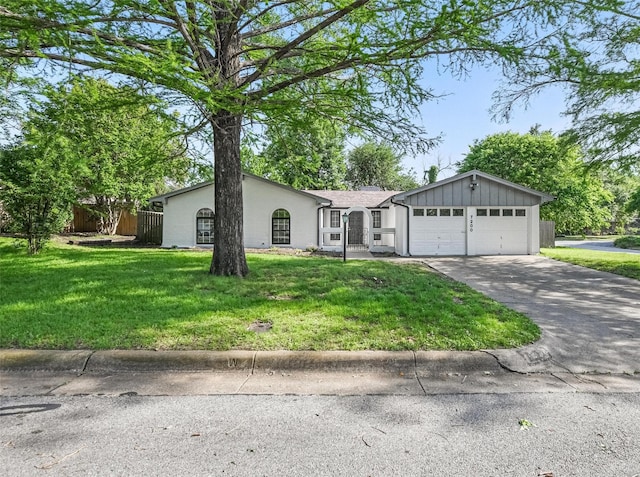 ranch-style house featuring driveway, stucco siding, an attached garage, fence, and a front lawn