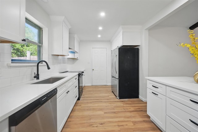 kitchen with recessed lighting, white cabinets, stainless steel appliances, a sink, and decorative backsplash