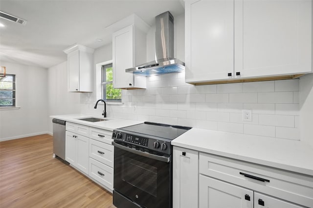 kitchen with wall chimney exhaust hood, light wood-style flooring, a sink, black electric range oven, and dishwasher