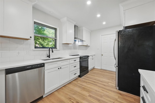 kitchen featuring stainless steel appliances, backsplash, wall chimney range hood, a sink, and light wood-type flooring