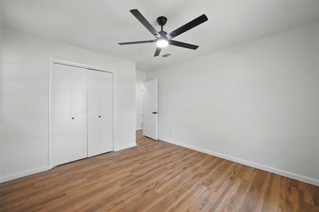 unfurnished bedroom with ceiling fan, baseboards, light wood finished floors, and a closet