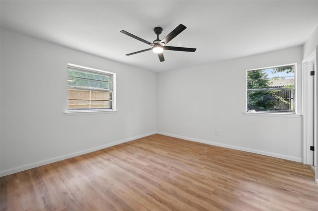 empty room with light wood finished floors, ceiling fan, a wealth of natural light, and baseboards