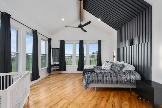 bedroom featuring beamed ceiling, light wood-type flooring, high vaulted ceiling, and ceiling fan