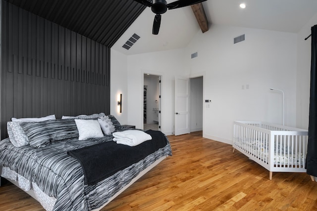 bedroom with a barn door, visible vents, beamed ceiling, light wood-style floors, and high vaulted ceiling