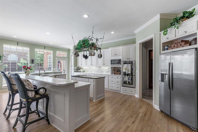 kitchen with crown molding, appliances with stainless steel finishes, white cabinetry, a large island, and tasteful backsplash