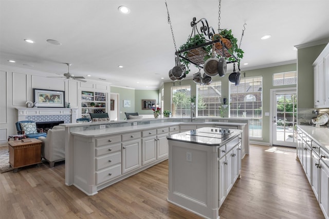 kitchen featuring crown molding, ceiling fan, a fireplace, open floor plan, and a kitchen island