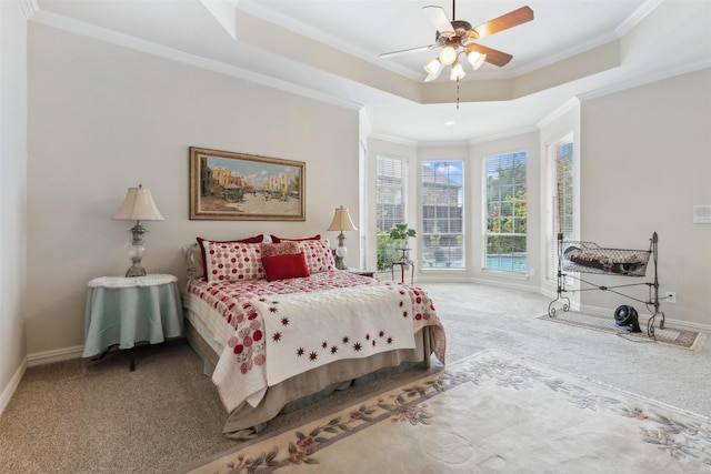 carpeted bedroom featuring crown molding, baseboards, ceiling fan, and a tray ceiling