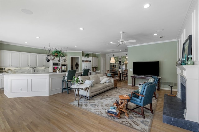 living room featuring recessed lighting, ornamental molding, and light wood-style floors