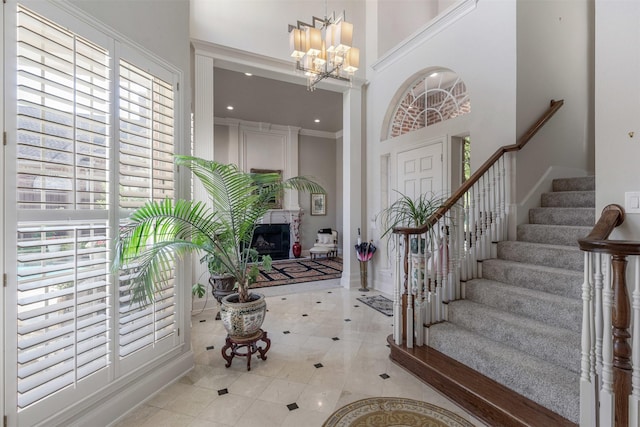 foyer entrance with tile patterned flooring, a fireplace, a chandelier, stairs, and a towering ceiling