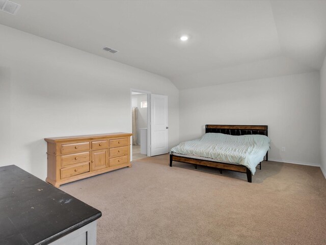 bedroom with lofted ceiling, visible vents, carpet floors, and connected bathroom