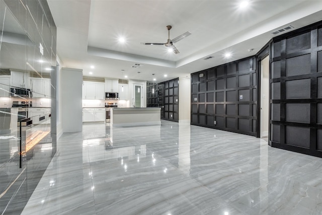 1963 Dennison St, Dallas, TX 75212 - unfurnished living room featuring a decorative wall, light marble finish floors, ceiling fan, recessed lighting, and a tray ceiling