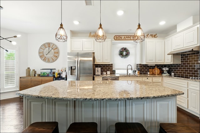 kitchen with a breakfast bar area, a sink, appliances with stainless steel finishes, and tasteful backsplash