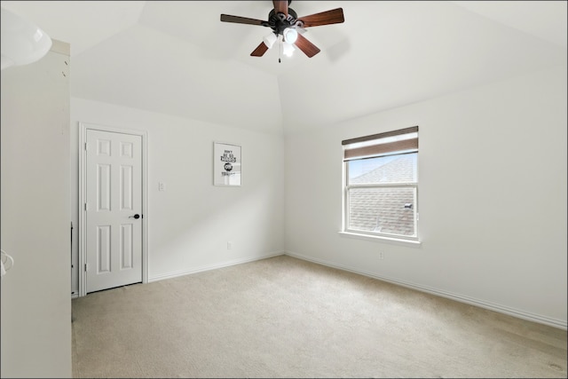 carpeted empty room featuring ceiling fan, lofted ceiling, and baseboards