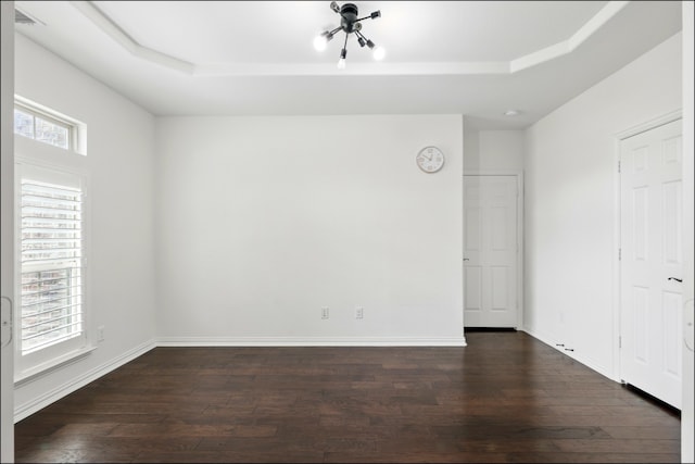 interior space featuring visible vents, baseboards, a raised ceiling, and dark wood finished floors
