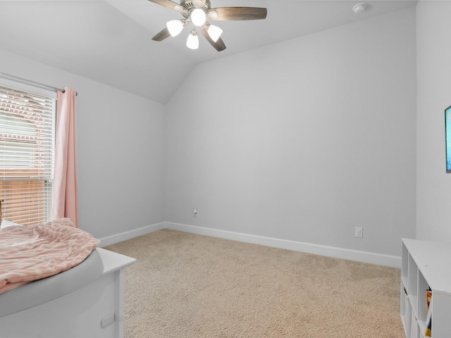 unfurnished bedroom with lofted ceiling, a ceiling fan, light carpet, and baseboards