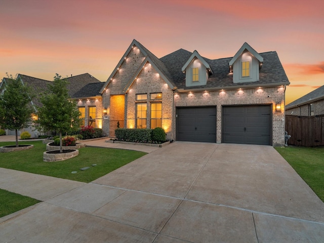 view of front facade featuring brick siding, fence, a garage, a front yard, and concrete driveway