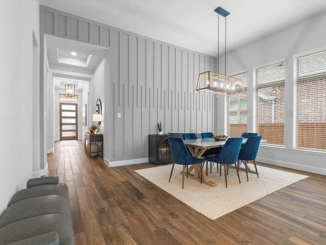 dining room featuring dark wood-style floors, a notable chandelier, and baseboards