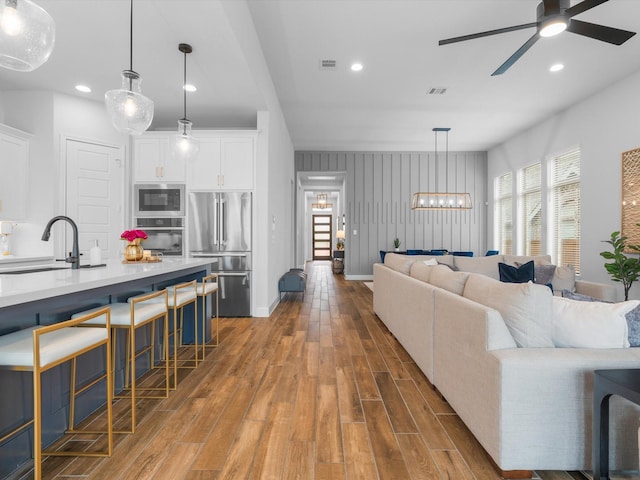 living room with recessed lighting, baseboards, wood finished floors, and ceiling fan with notable chandelier