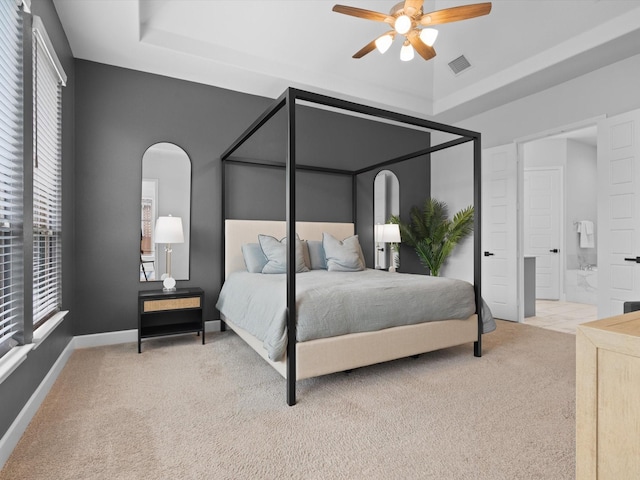bedroom with visible vents, a tray ceiling, arched walkways, and carpet floors