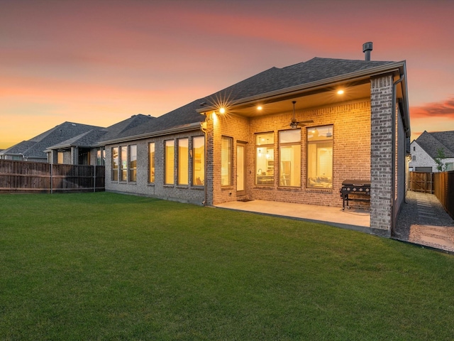 back of property featuring brick siding, a fenced backyard, a yard, and a patio area