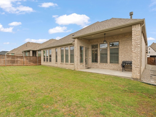 rear view of property with a fenced backyard, a yard, brick siding, ceiling fan, and a patio area