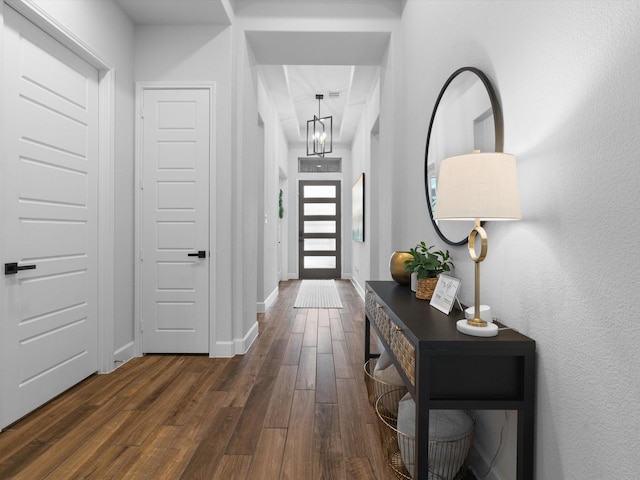 interior space with dark wood-style flooring, a chandelier, and baseboards